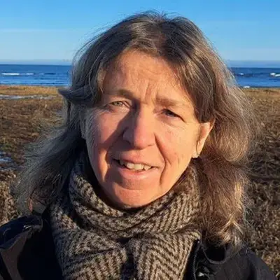Äldre kvinna med halsduk står ute i naturen