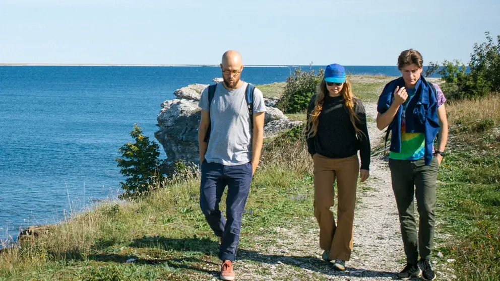 Tre personer som vandrar längs havet