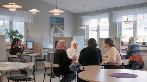 Elever som sitter vid borden i studieteket.