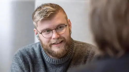 Kille med glasögon som pratar med någon som inte syns i bild.