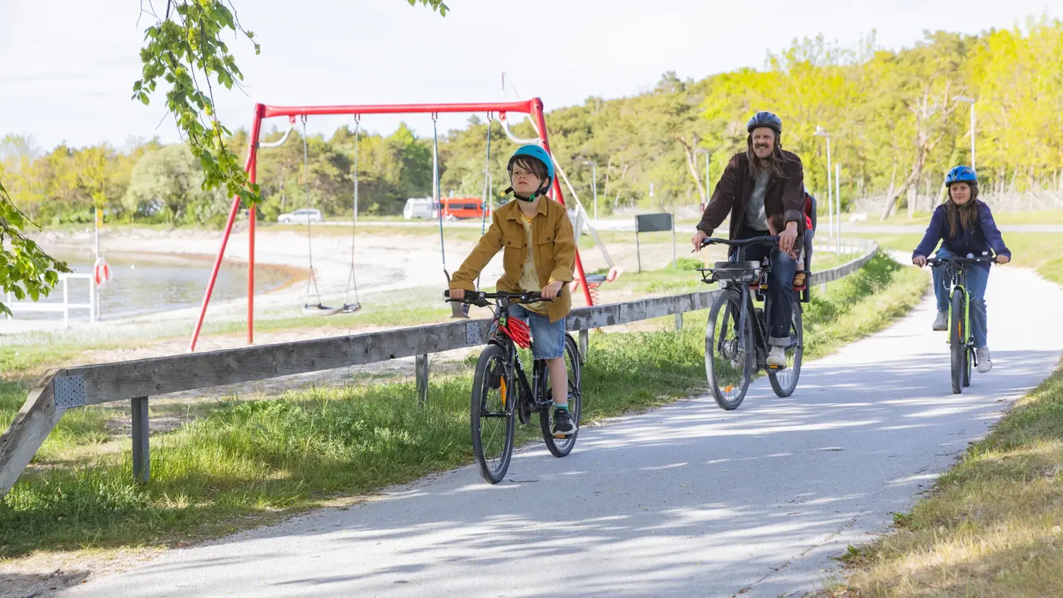 Familj som cyklar på cykelväg nära strand