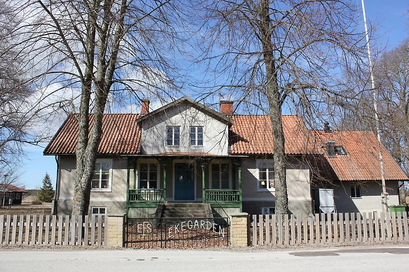 Envånings byggnad med vita fönster, en blå ytterdörr och ett rött tegeltak.