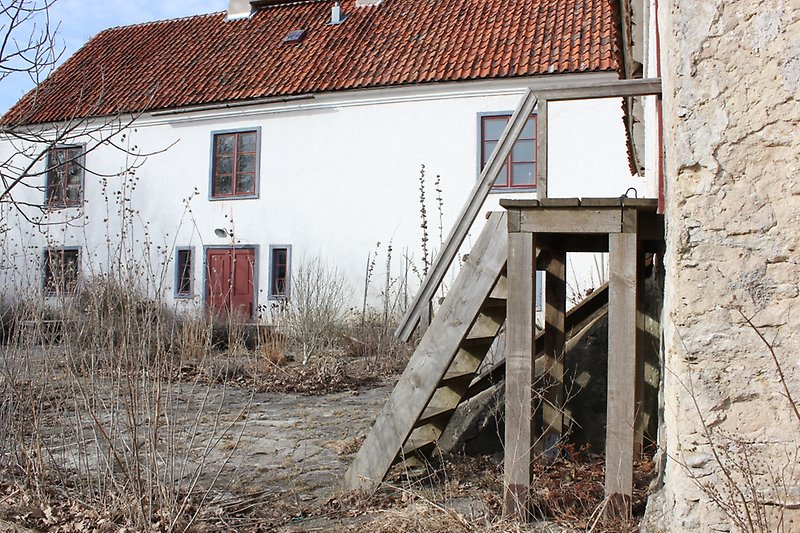 Ett vitt tvåvåningshus med röda fönster, röda dörrar, gråa fönsterramar och gråa dörramar.