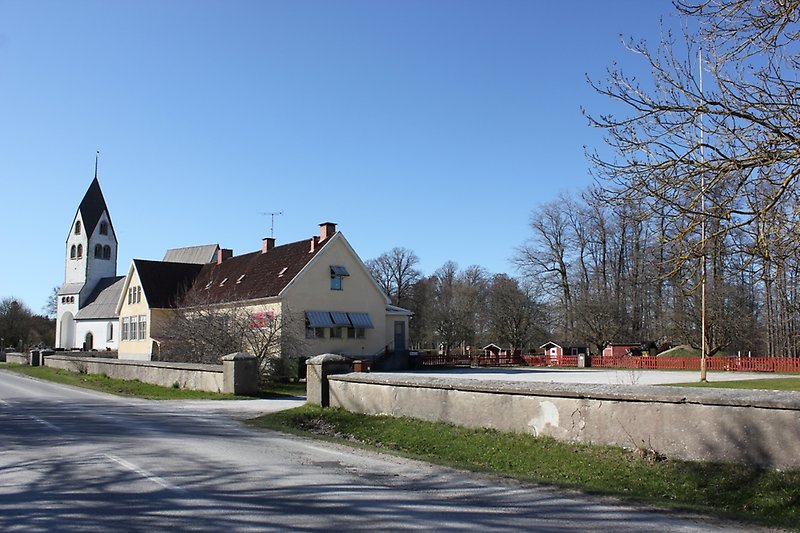 Närmast vägen ser man en skolgård, sedan kommer skola och därefter står det en kyrka.