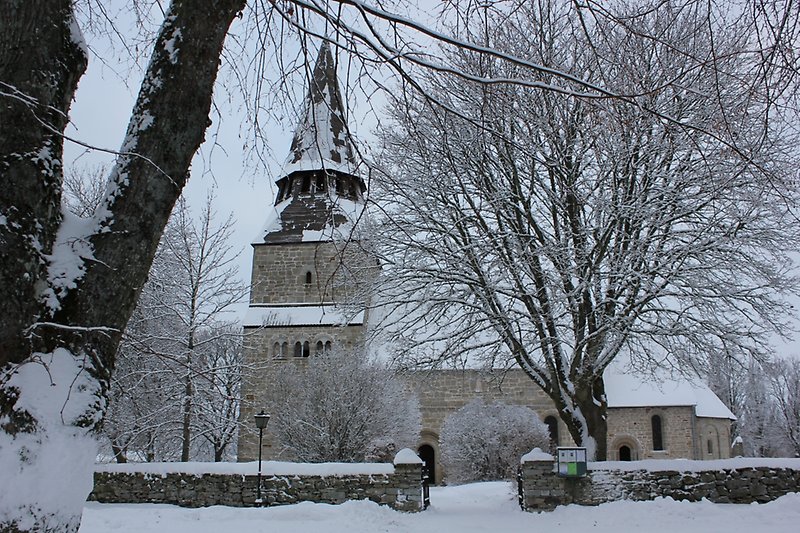 Innanför stenmuren ligger det en stenkyrka med ett svart tak.