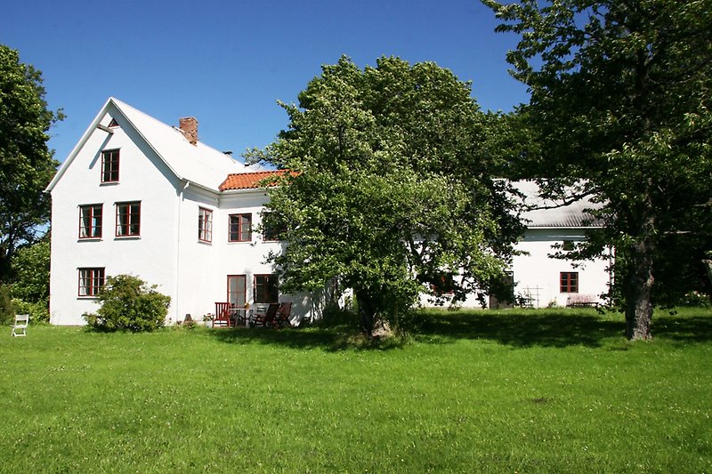 Ett vitt tvåvåningshus med röda fönster.