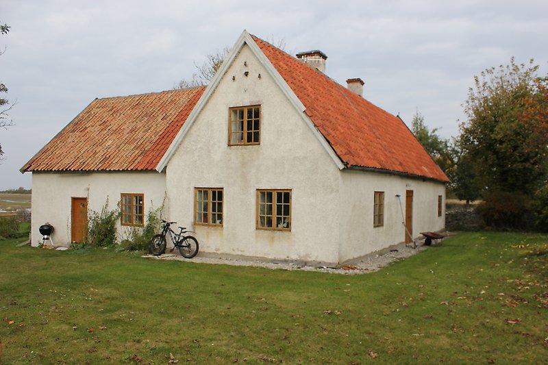 En tvåvånings hus med rött tak, ljusbruna fönster och en bruna dörrar.