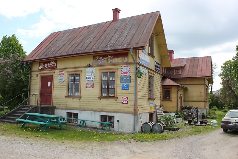 Ett gult hus med träfasad, ett rött plåttak med en skorsten.