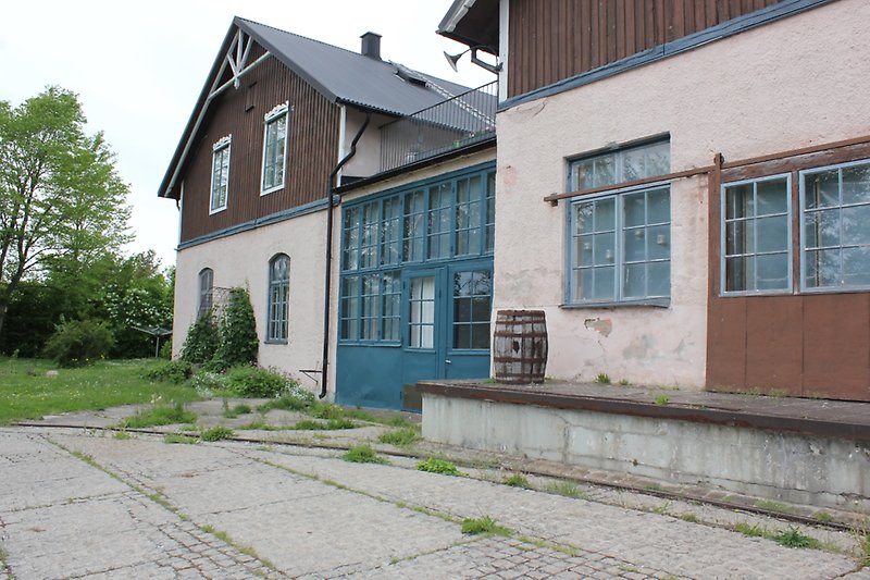 En brunvit byggnad med blåa fönster och ett svart plåttak.