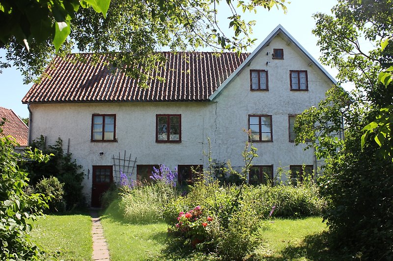 Ett stort vitt hus med bruna fönster, bruna dörrar och ett brunt tegeltak med en skorsten.