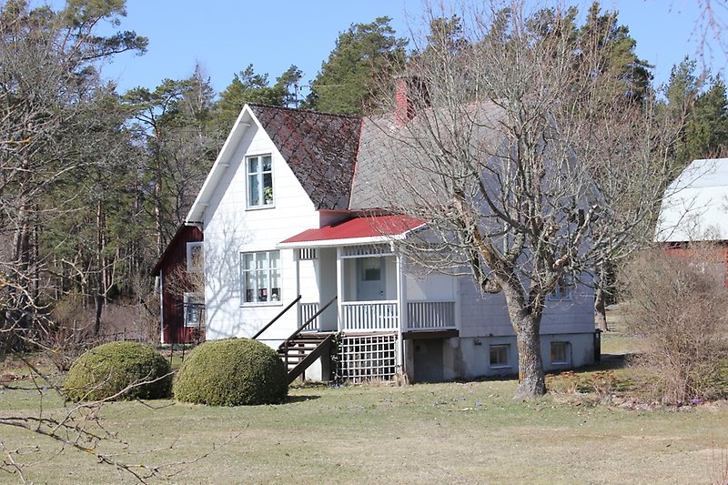 Ett vitt hus med en skorsten och ett rött tak.
