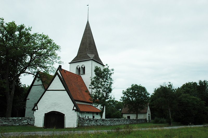 En kyrka med en stenmur på kyrkogården.