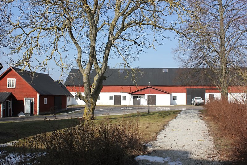 En rödvit lada med ett svart plåttak.