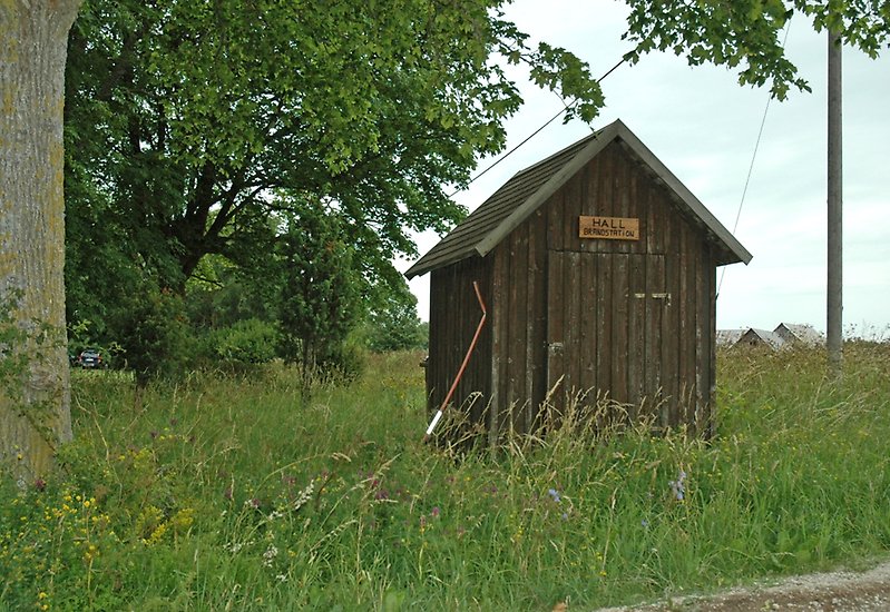 En liten träbyggnad bland det höga gräset.