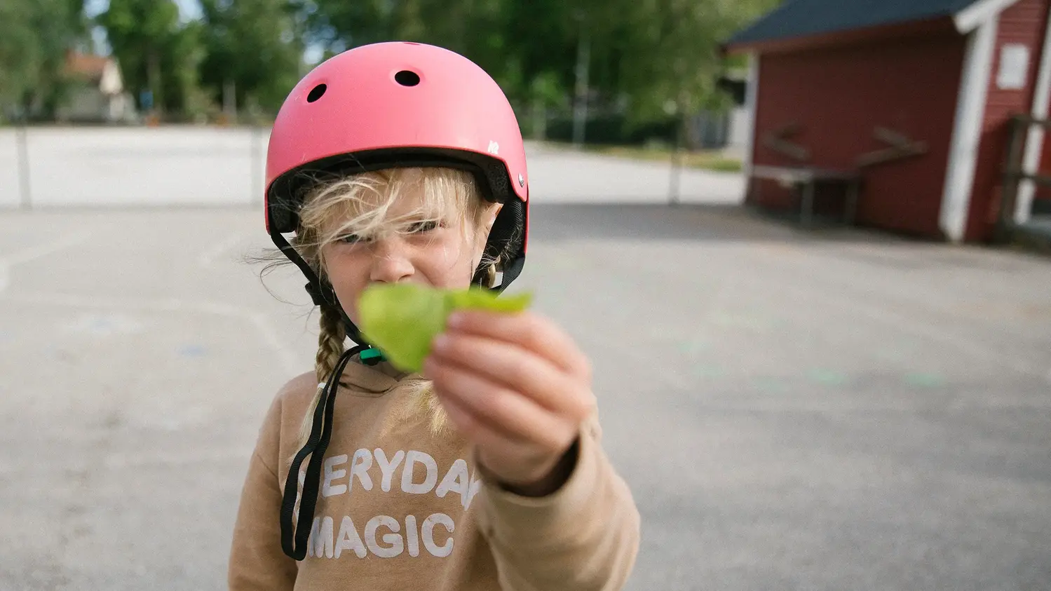 Barn med rosa hjälm håller upp ett löv