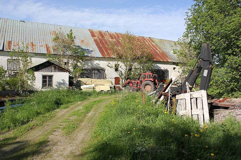 På baksidan av den vita ladan står det en röd traktor.