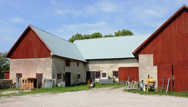 En vit lada med delvis röd träfasad och ett rött plåttak.