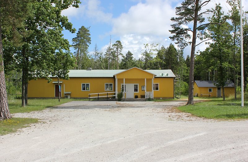 En gul bygdegård med vita fönster och ett plåttak.